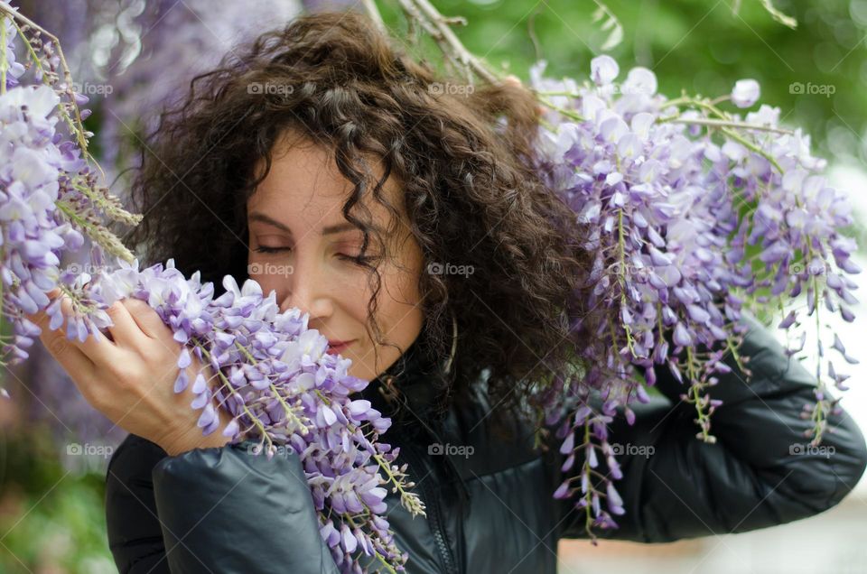 Woman with beautiful curly hair on a background of Wisteria