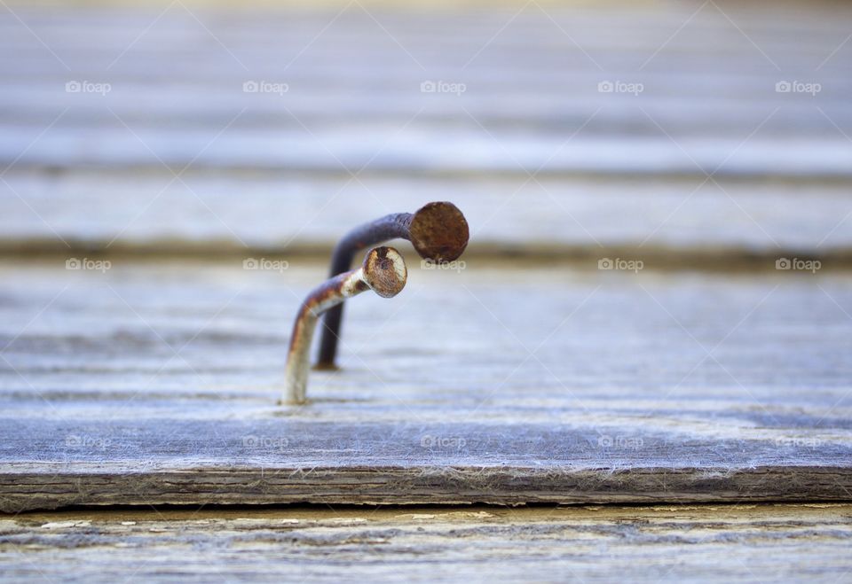 Closeup of two rusty, bent nails in weathered wood