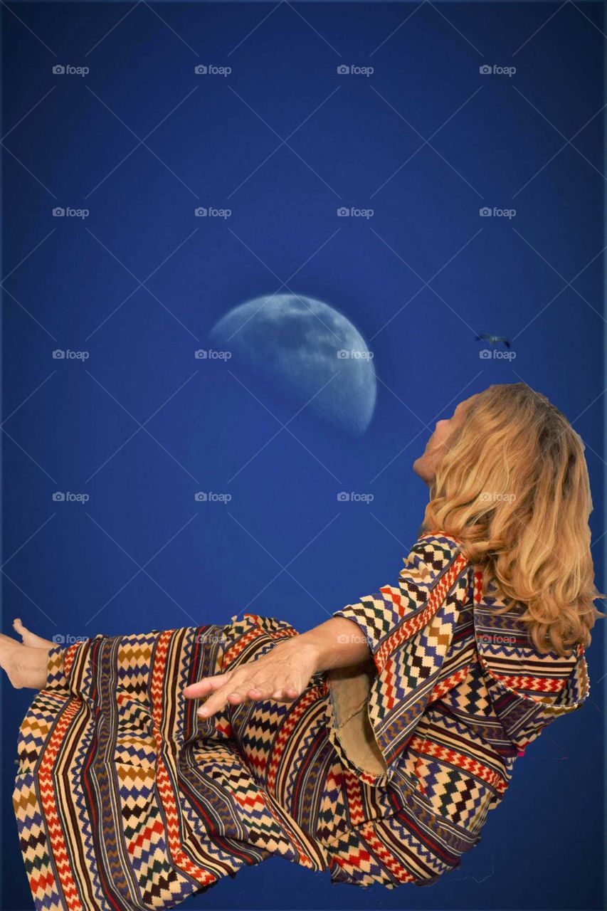 Woman in kaftan floating in the air with half moon and bird