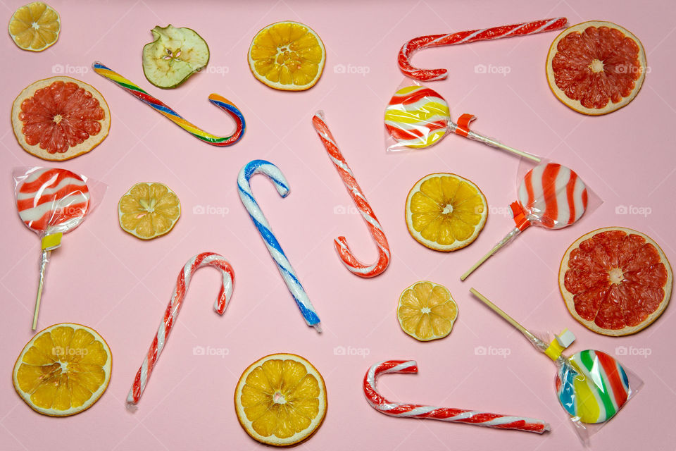 Lollipops and dried fruit layout on pink background