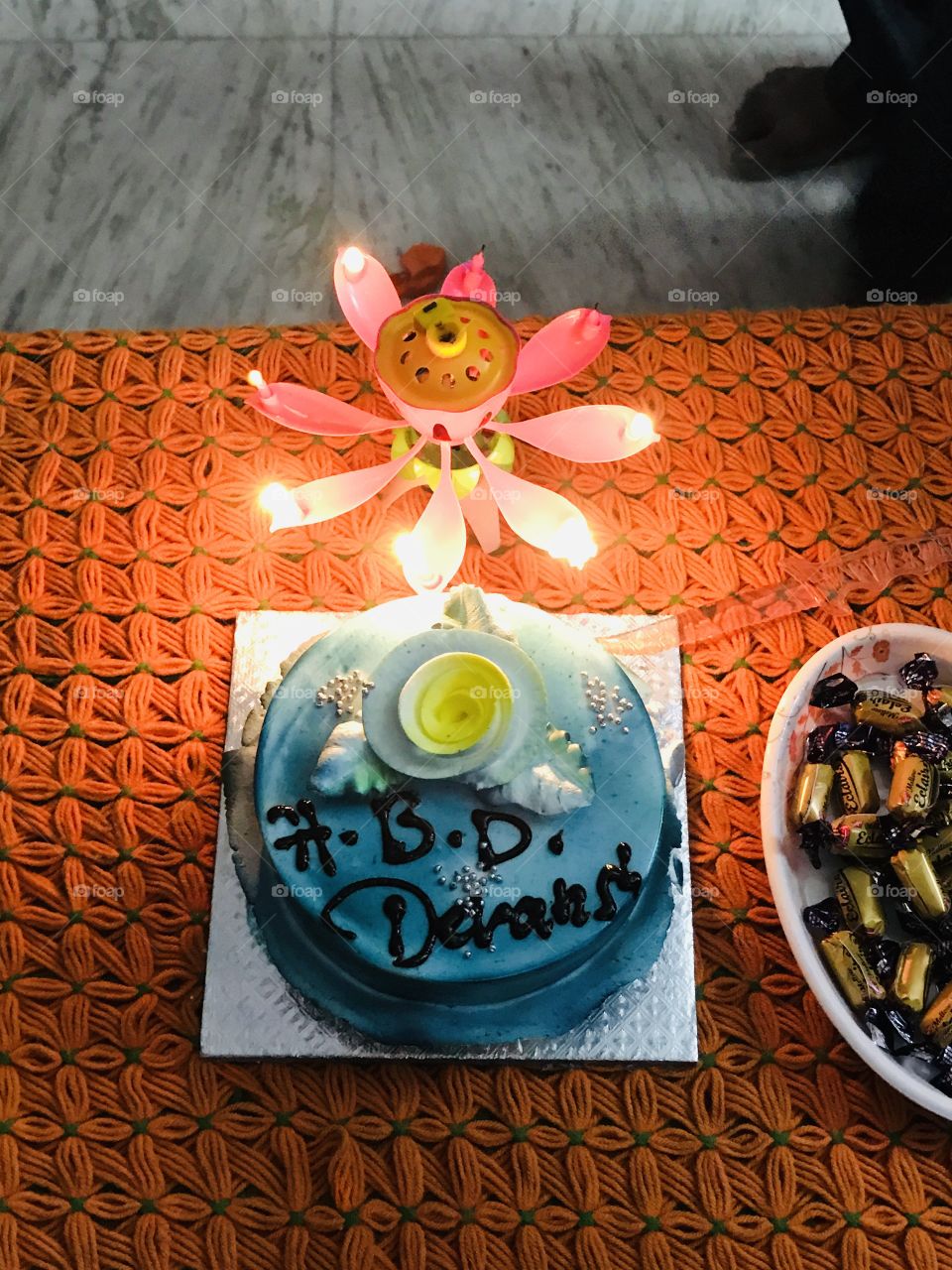 Birthday cake with bright candle light and plateful of chocolates 