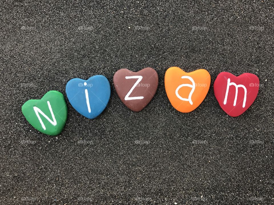 Nizam, masculine name with colored heart stones over black volcanic sand