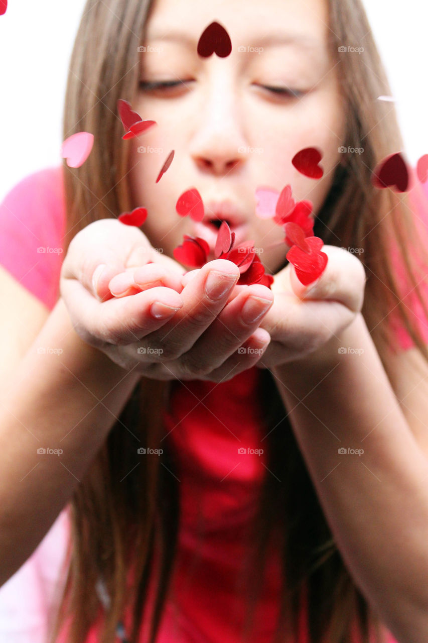 Portrait of young girl blowing hearts from her hand