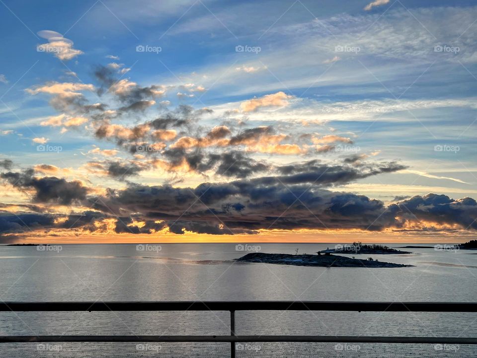 Stunning sunrise horizon over Baltic sea with sunlight behind  low dark clouds and small islands overboard