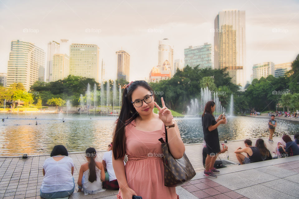 A Thai girl poses in front of a view of Kuala Lumpur city.