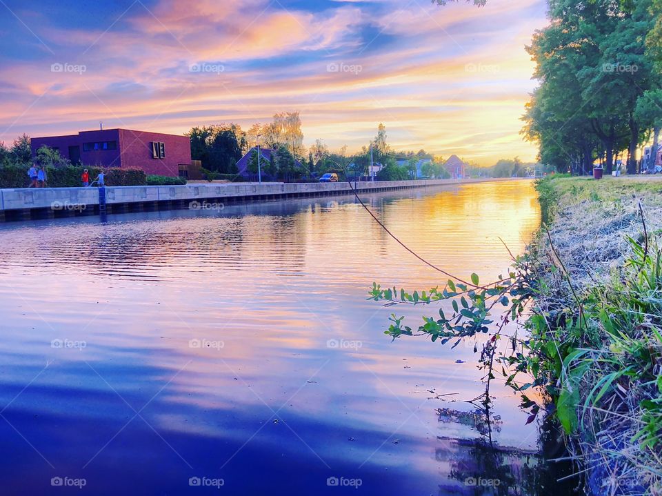 Dramatic and colorful idyllic sunset or sunrise reflected in the water of the river or canal