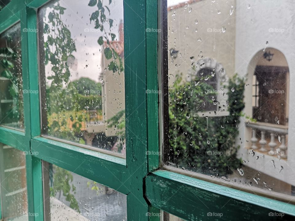 Raindrops at glass of window in city.