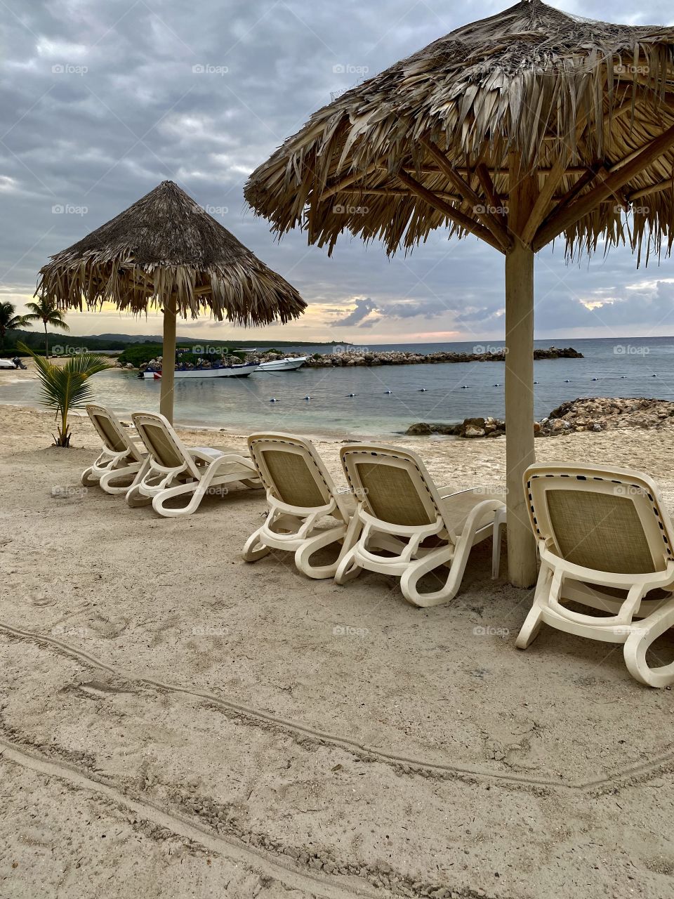 Sunset by a beautiful beach in the Bahia Principe Grand Jamaica hotel area with chaise lounges in front of it 