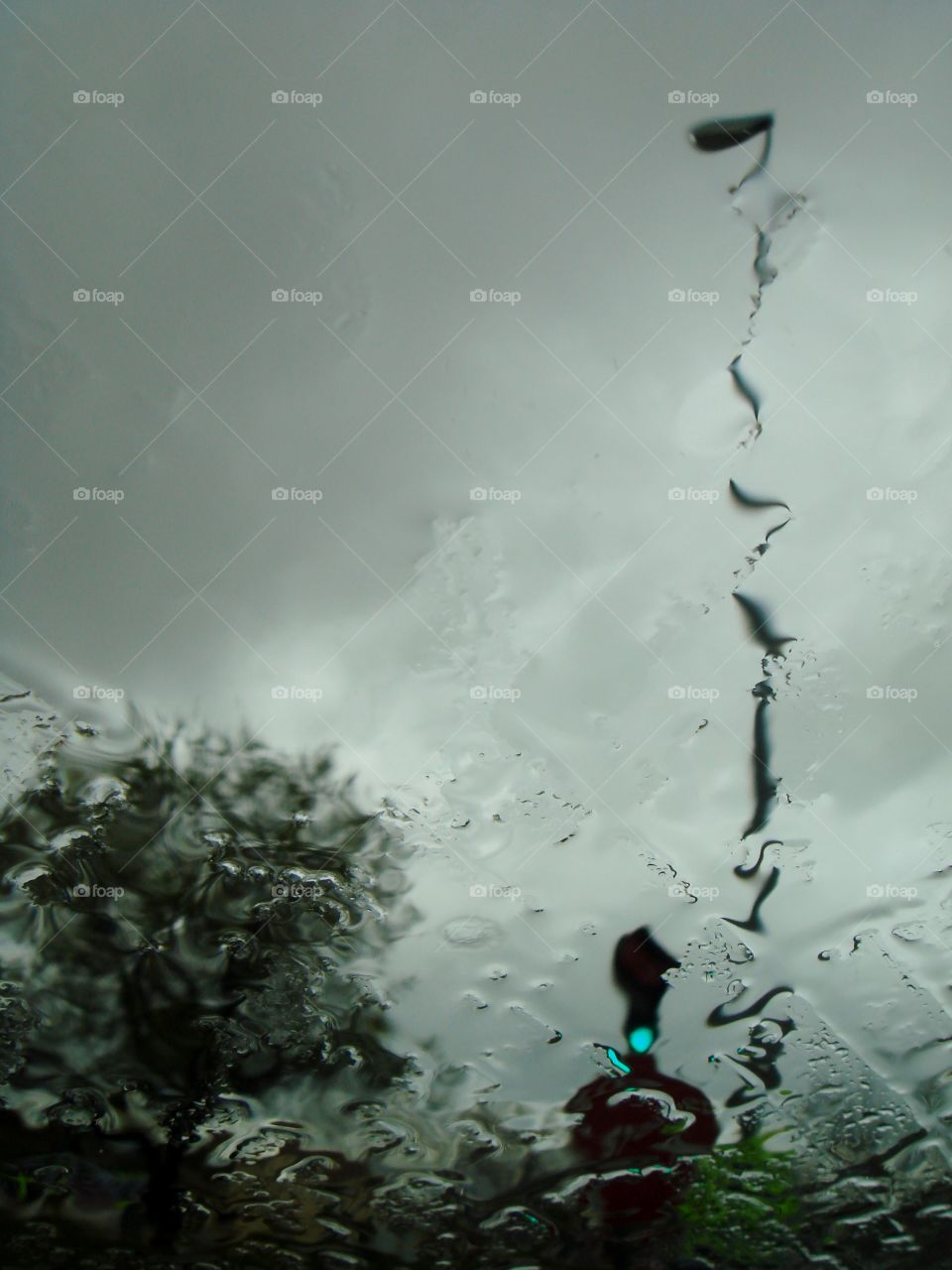 the traffic light is green, it is raining and the window is dripping