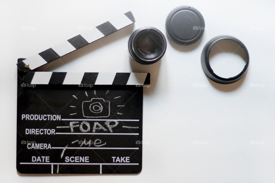 Clapboard and photo lens on white background