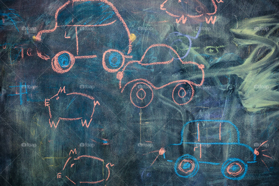 Childish colorful chalks drawings on blackboard depicting cars and characters