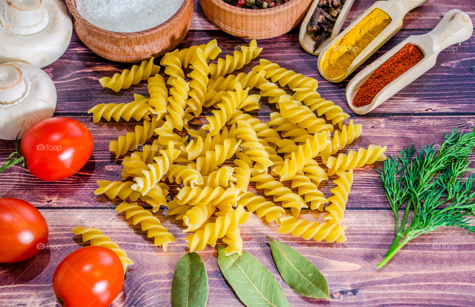 Raw pasta with ingredients and wooden accessories
