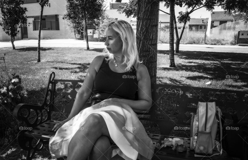 Una foto en blanco y negro , representando a una mujer con la mirada puesta hacia el horizonte , mientras sus hijos juegan en el parque. Su falda de gasa  Hugo Boss esta subida con una despreocupada elegancia como señal de protesta .