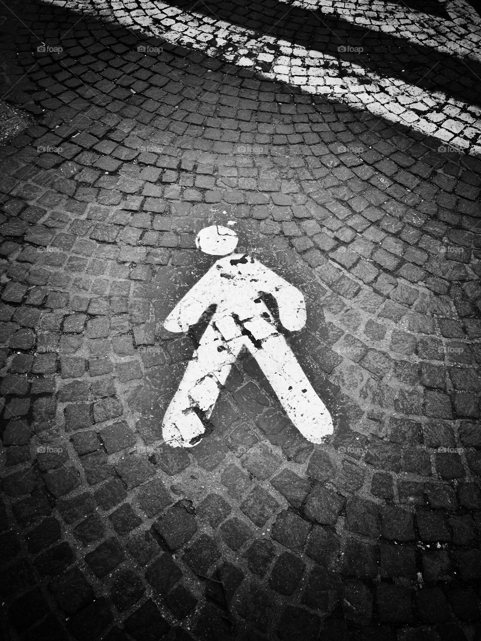 Black and white pedestrian icon on a cobblestone street
