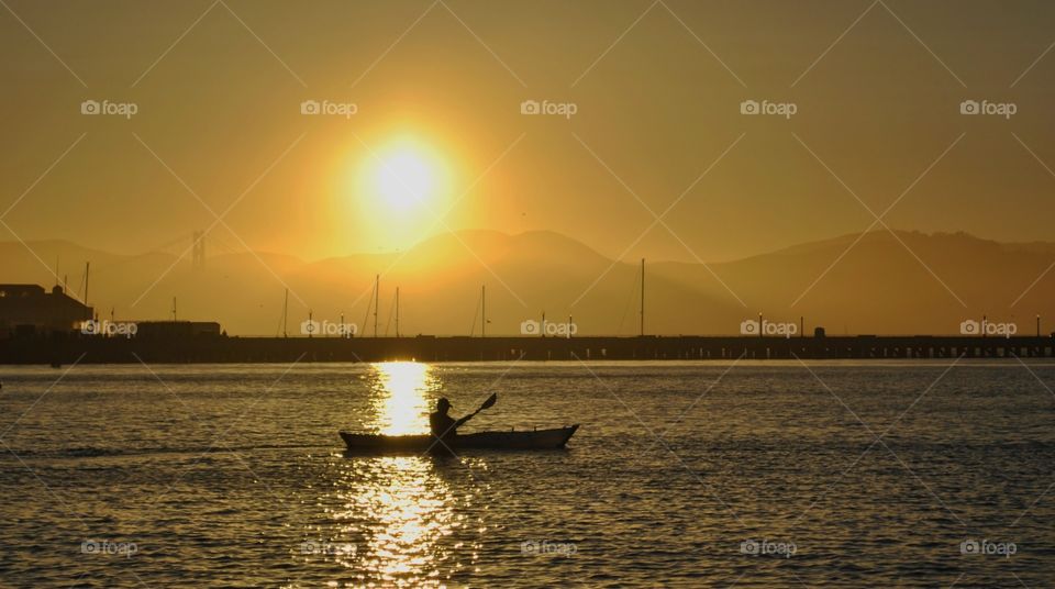 Kayaker paddling during sunset.