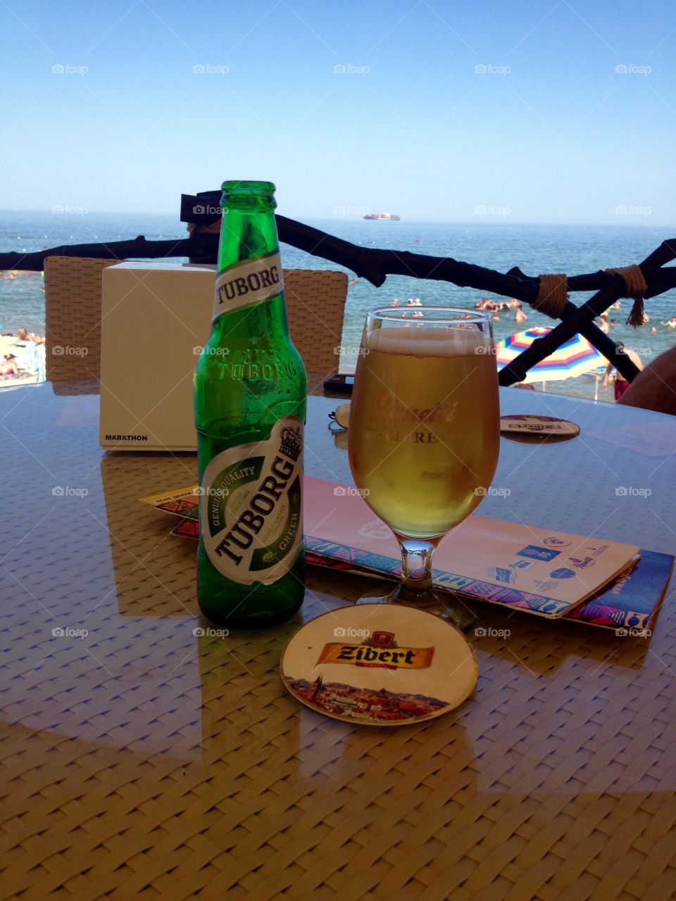 A beer and a glass on a table in the sea coast cafe