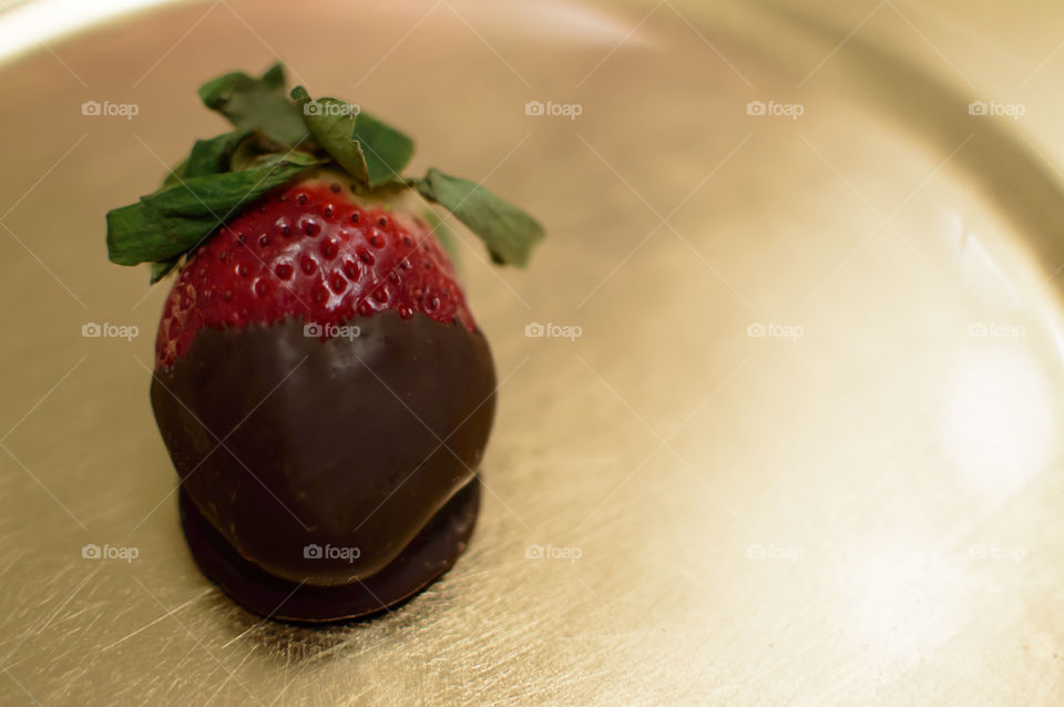 Strawberry dipped in chocolate on golden plate 