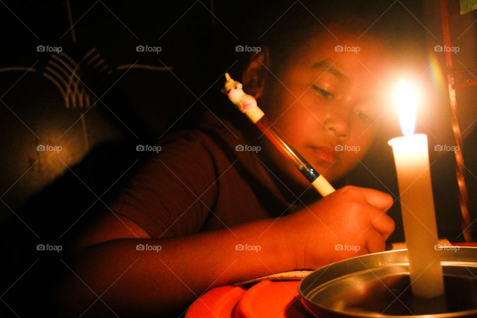 Jakarta, August 4, 2019 - a child writing on her book. She was in the dark room because of there was a blackout moment