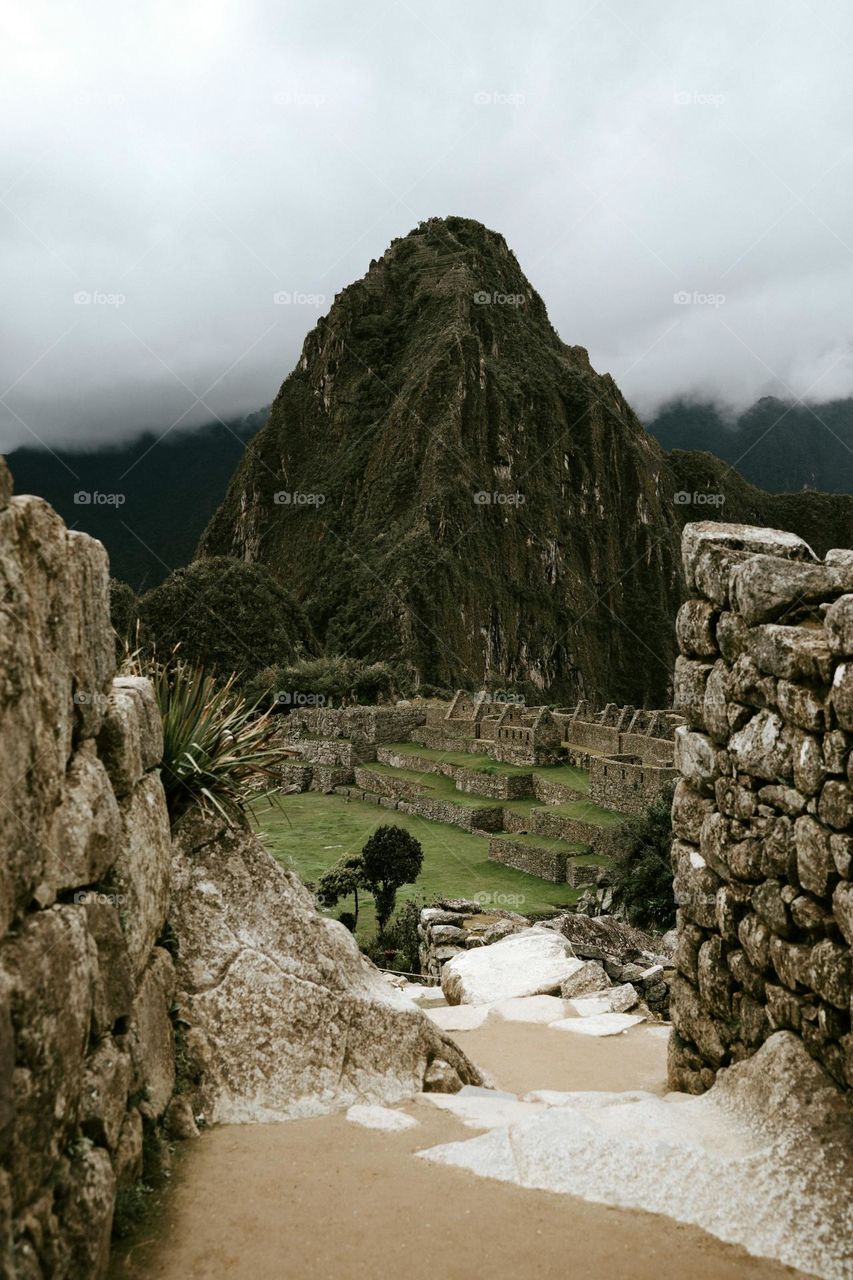 A dirt path leading to a stone structure with a mountain in the background