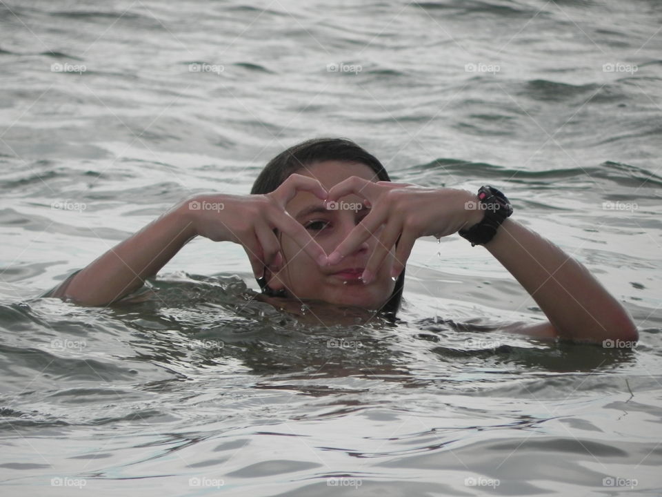 A woman in water making heart shape