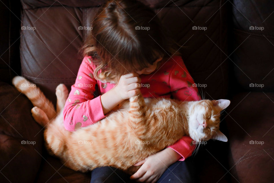Young Child Holding Orange Tabby Cat