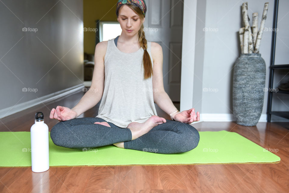 Millennial woman doing yoga and meditating on a hardwood floor