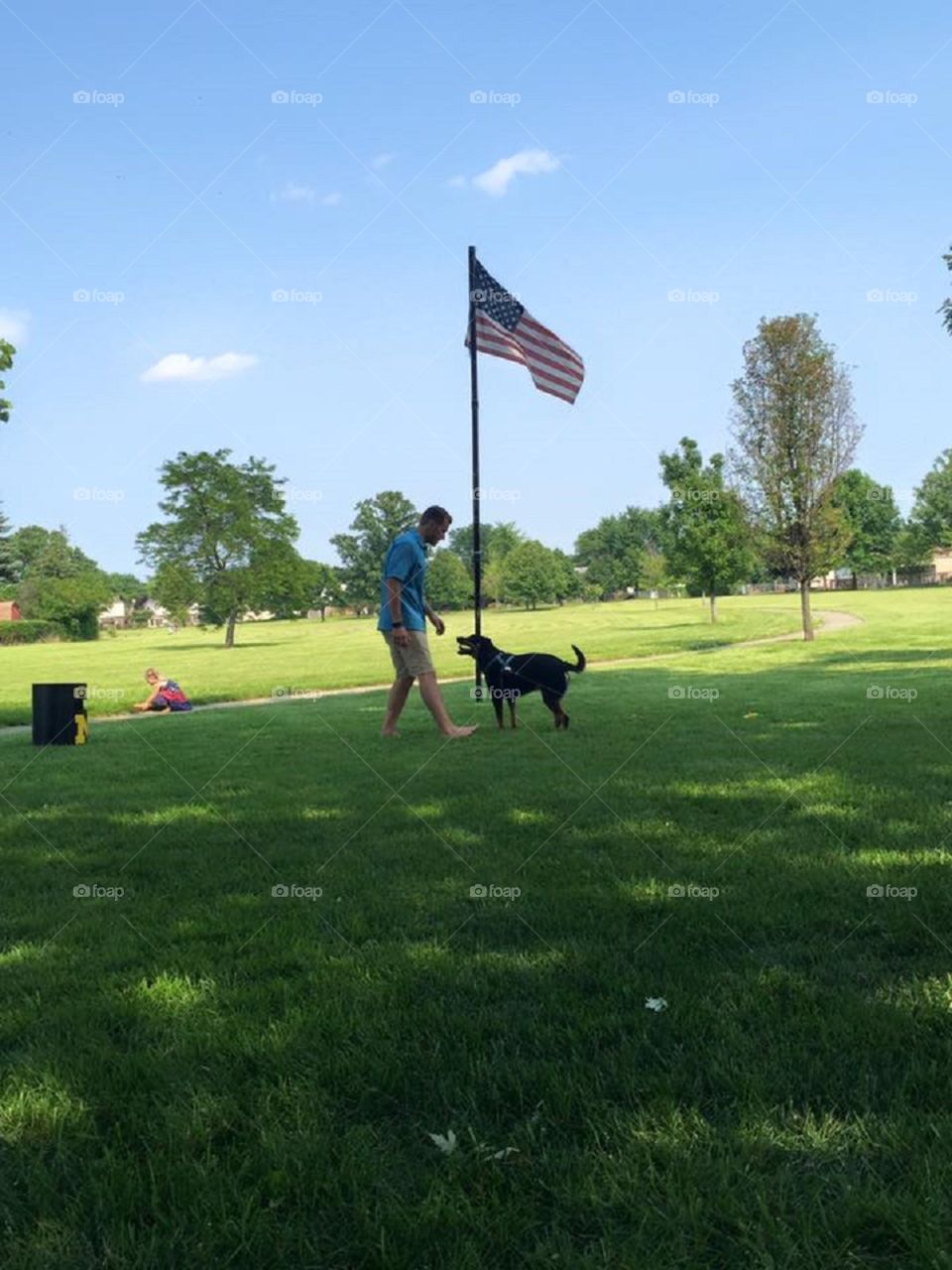 Man with dog and american flag at park