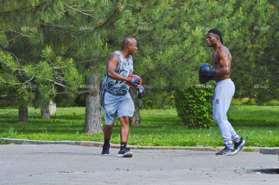 boxing trainer and his student training in the park