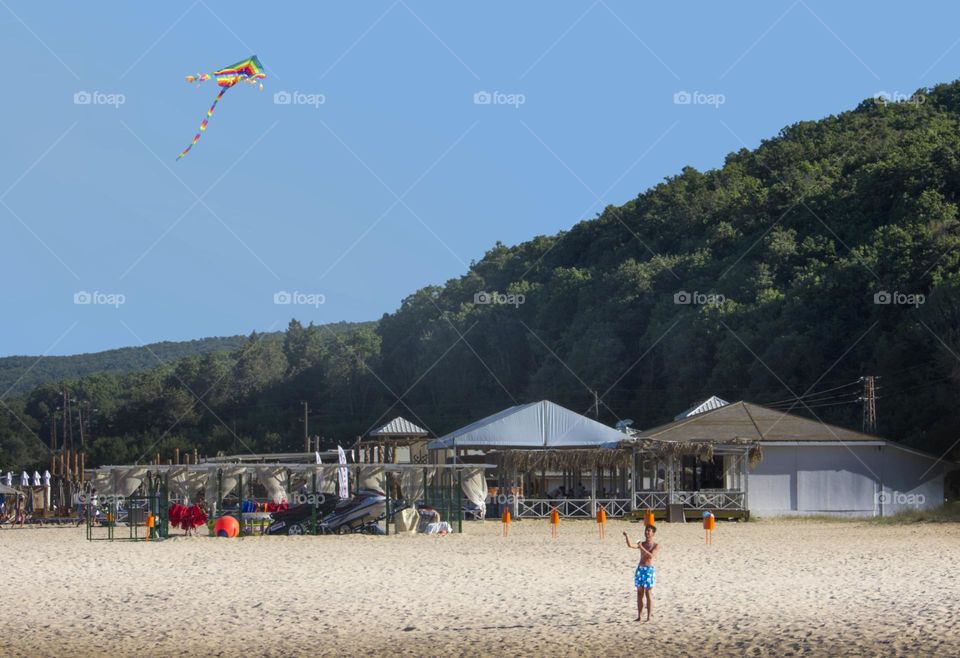 Boy and his colorful kite on the beach