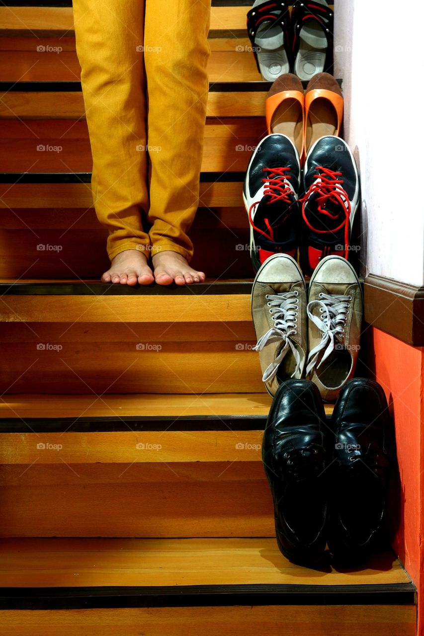 person standing beside shoes on staircase