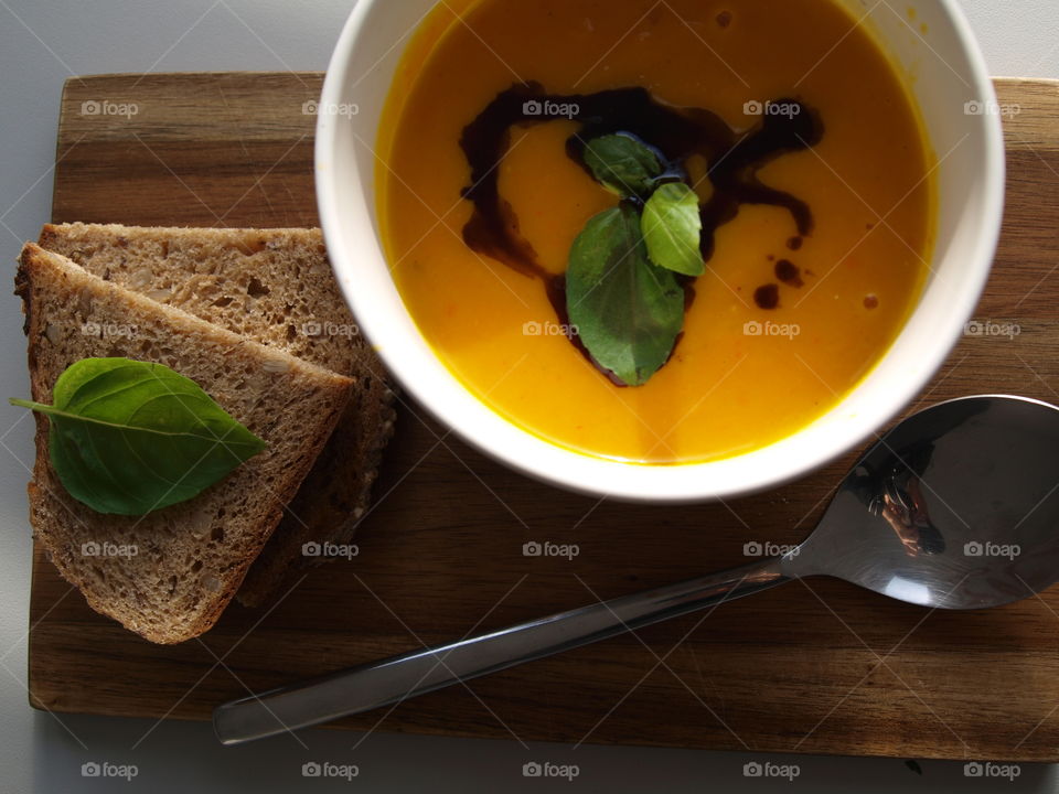 pumpkin soup to warm up after being outside in the cold, decorated with basil and fresh bread on the side