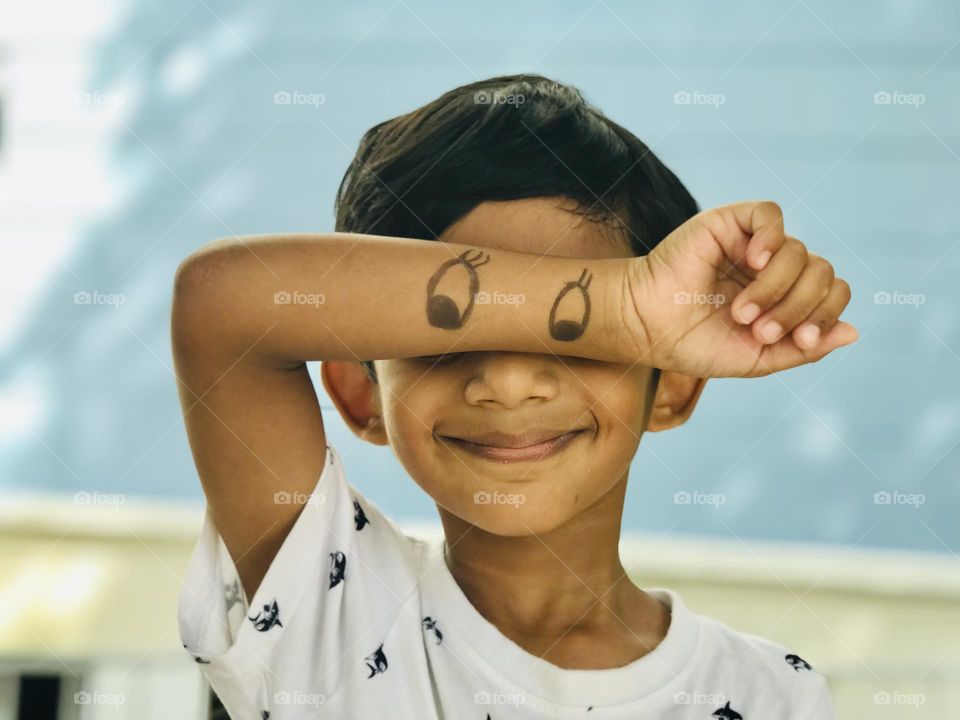 Fun with kids , here the boy replaced Mickey Mouse eyes on his eyes by drawing on his hand .and he gives cute smile.