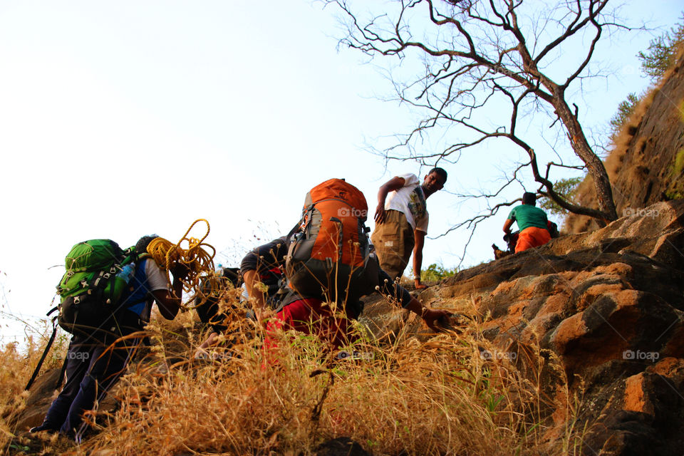 People hiking mountain with backpacks and ropes