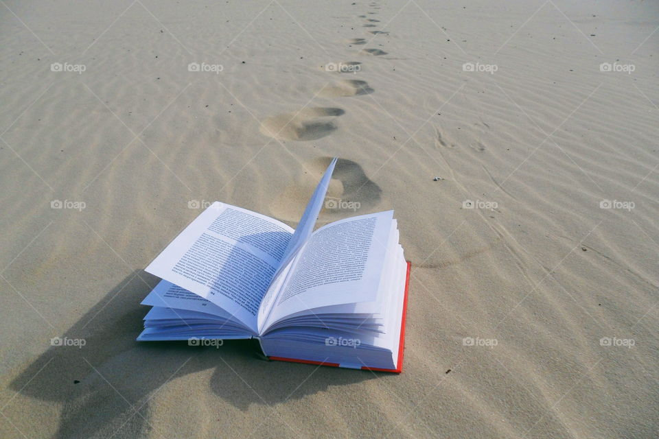 An open book lies on the sand