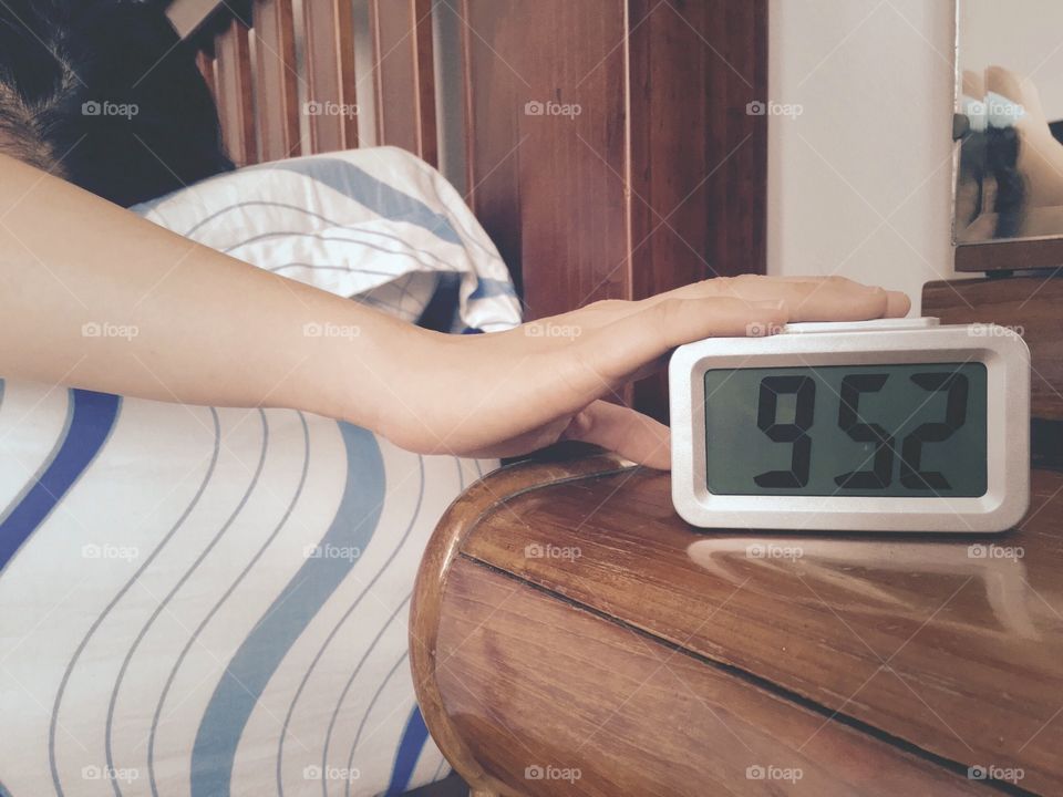 Hand of woman touching digital alarm clock for stop ringing sound