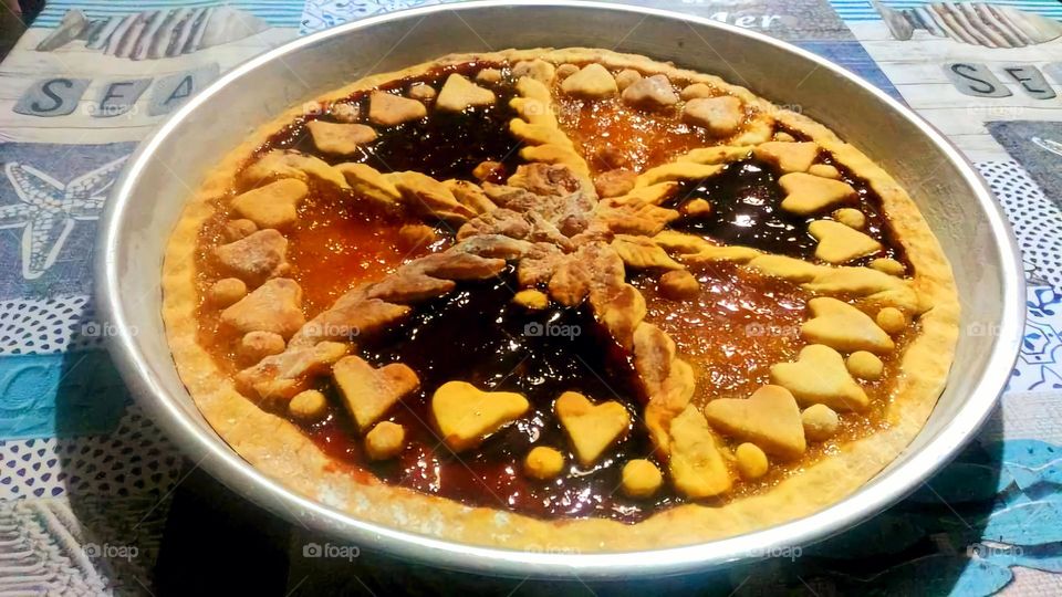 Two-flavoured tart with apricot and prune jam and heart-shaped pattern in an iron tray