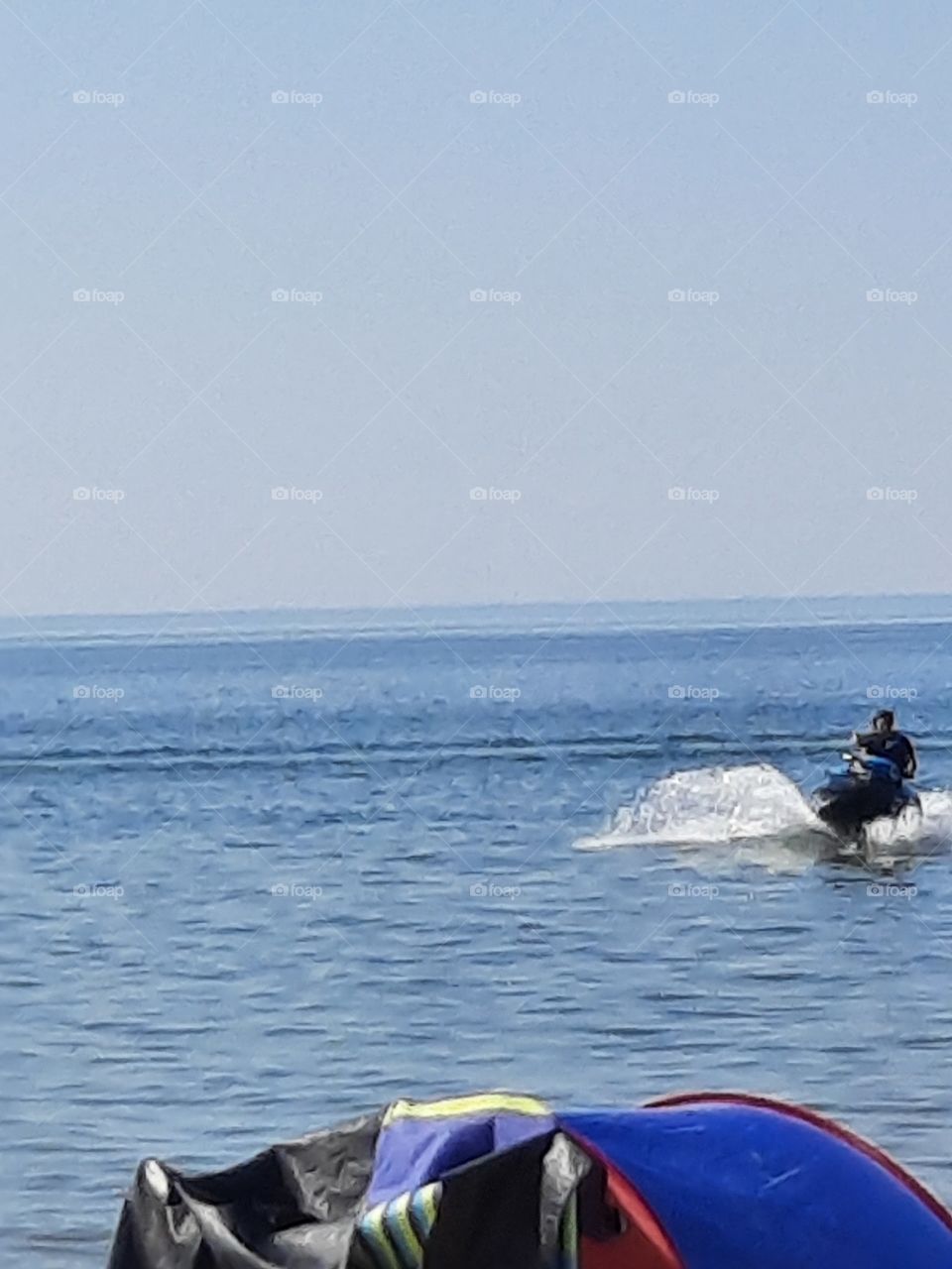 man on a jet ski approaching seashore showing large splash  !