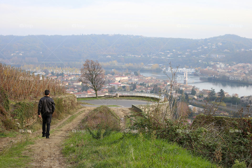 Man walks alone on country road from a hill. River landscape top view