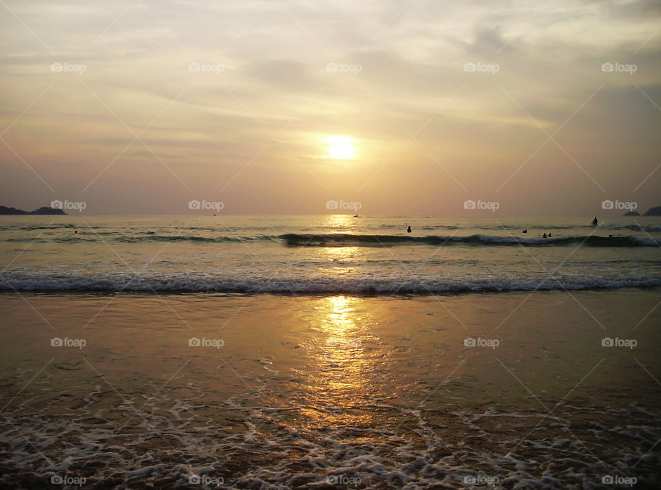 Enjoying the last summer days watching the tropical sunset above the sea 