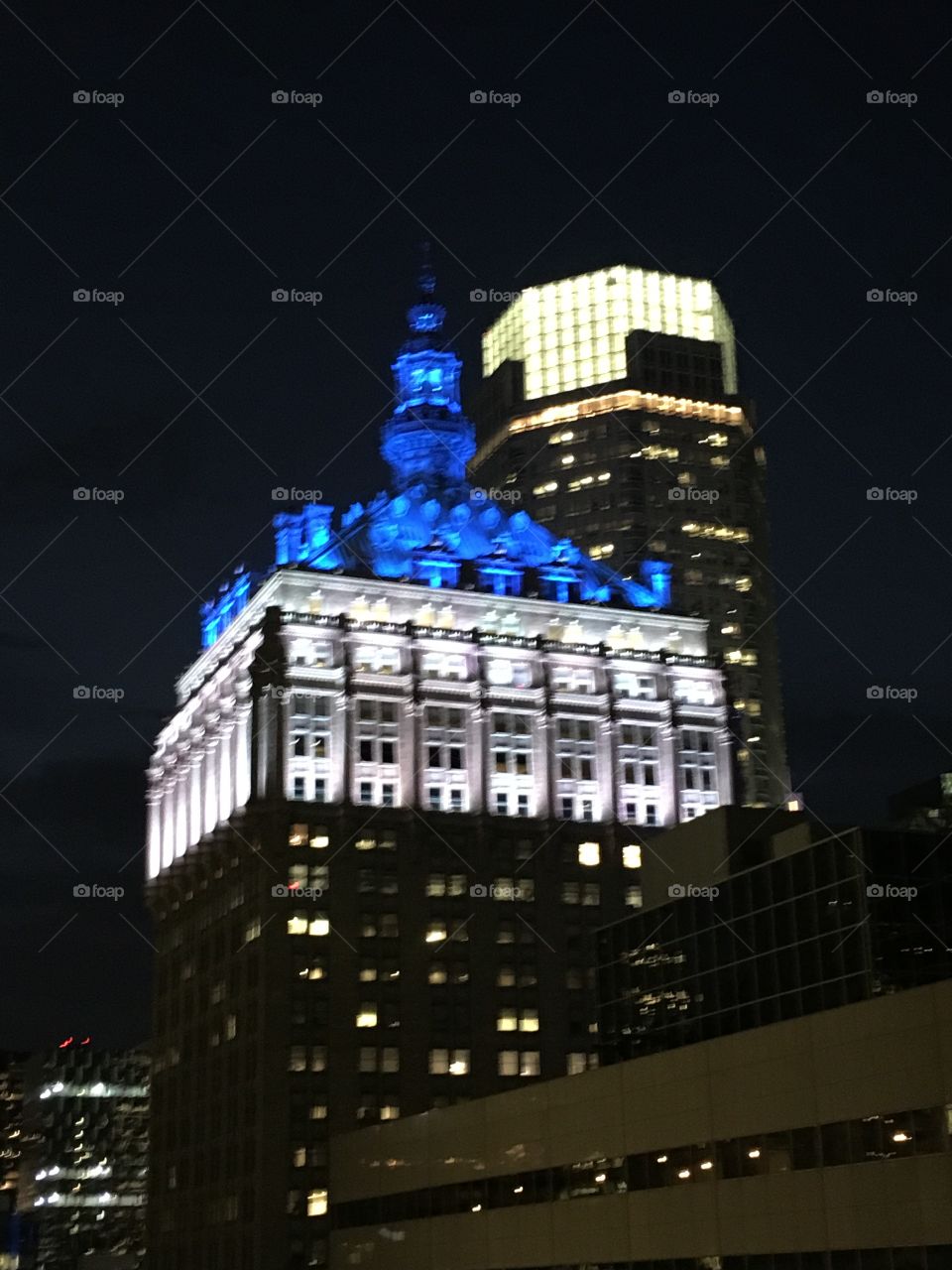 Watch the skyline light up the night. Blue and white illuminated building in city core. 