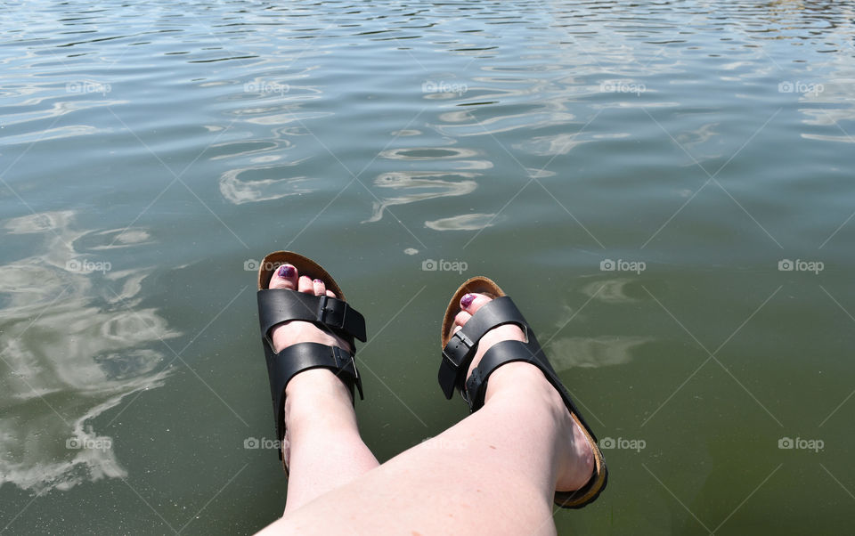 Woman's feet over water on the river bank