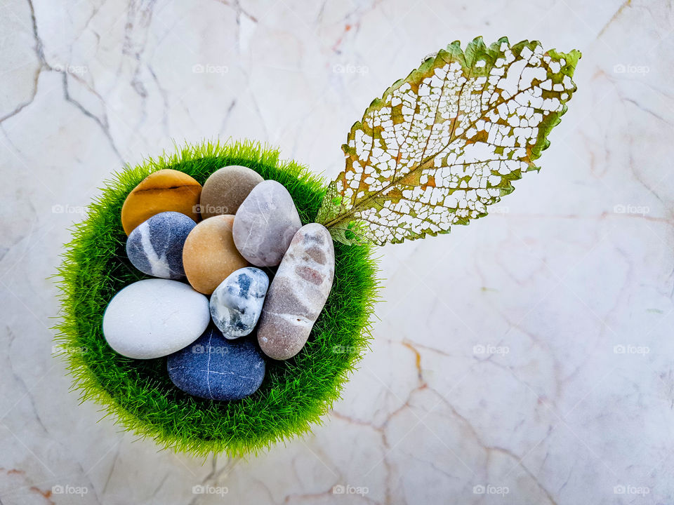 colourful pebbles on a grass vase decorated with a fallen leaf of a tree, the pattern on the leaf is all natural