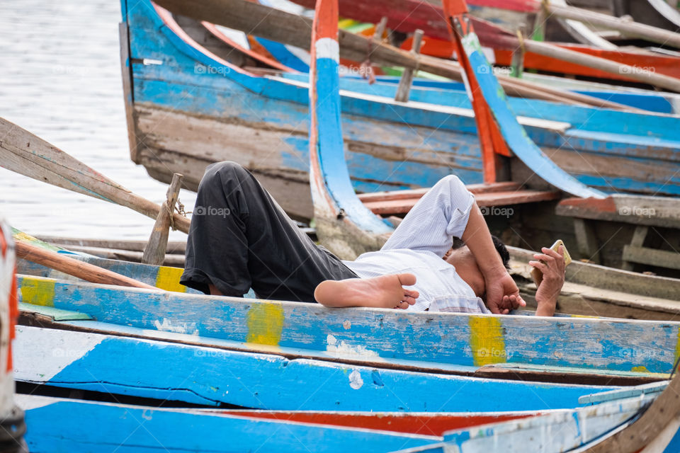 The world in his hand , local fishermen is using his smartphone while waiting tourists in his boat