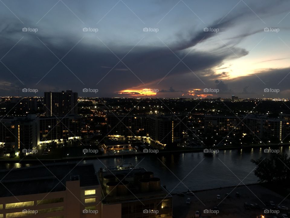 This is a beautiful sunset taken from a skyscraper in miami florida during a cloudy day in summer, it looks amazing how the sun light is just peeking threw the clouds
