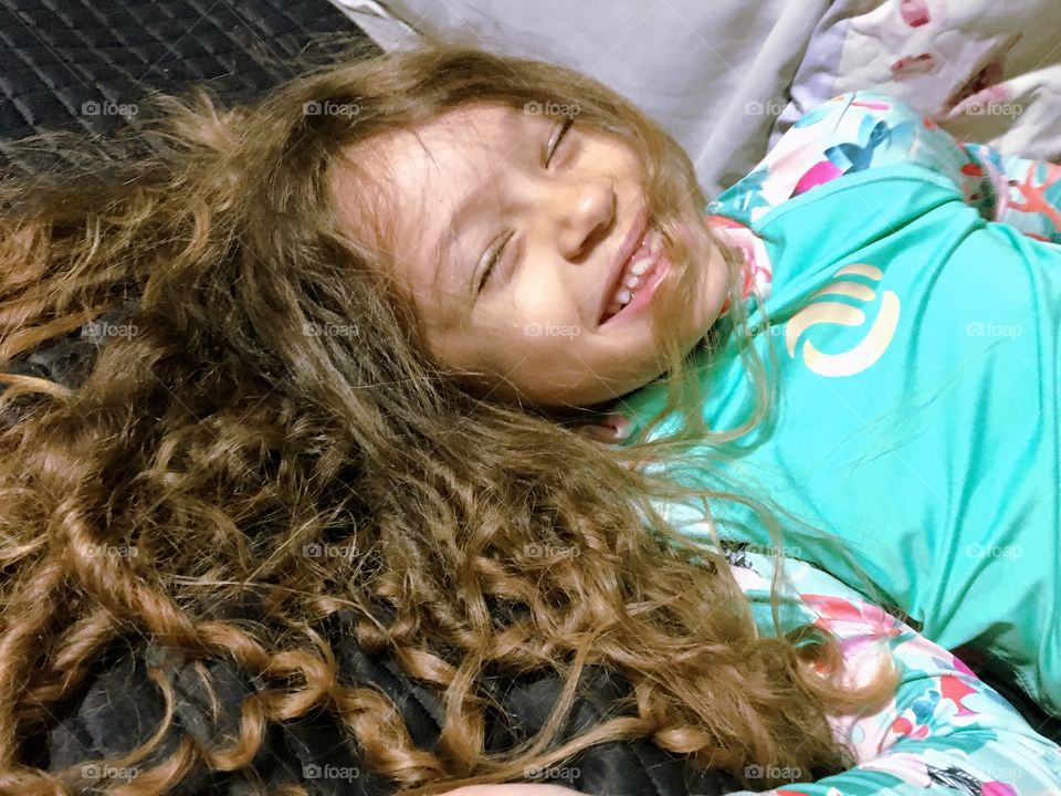 Little girl laughing a lot in her parents bed