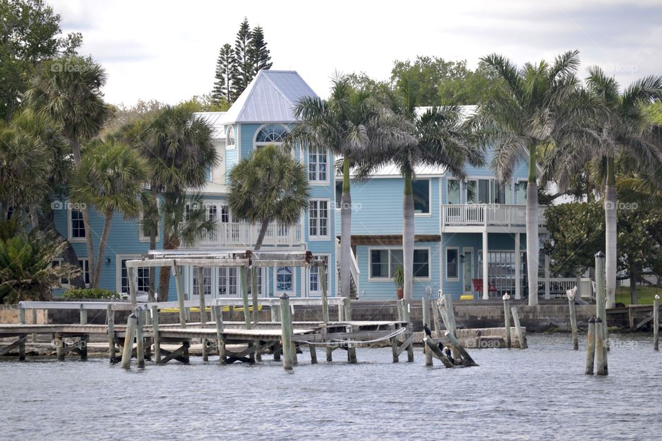 A big blue house on a river with a dock in front
