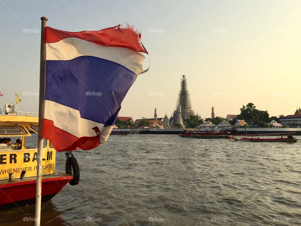 Thailand river and flag looking at temple Wat Arun in Bangkok 