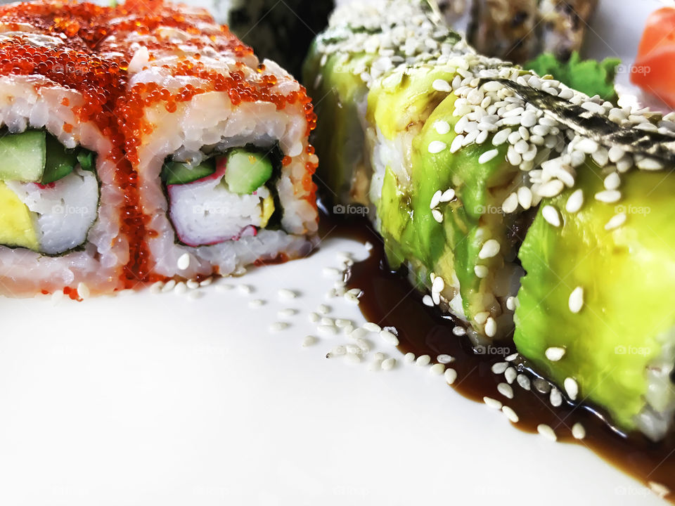 Colorful sushi set with sesame seeds on white plate 