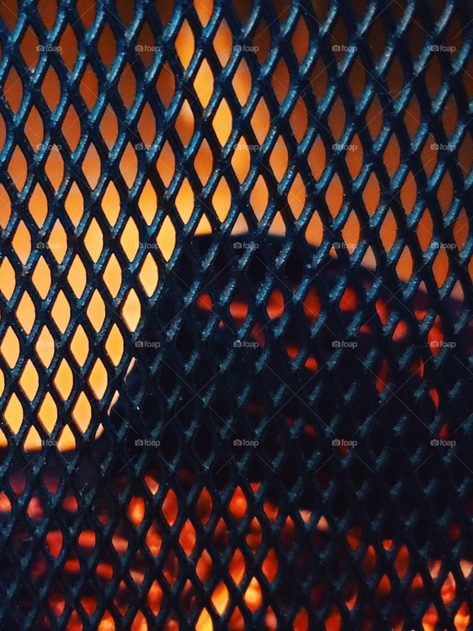 Fire glowing through the steel gate in a fire pit