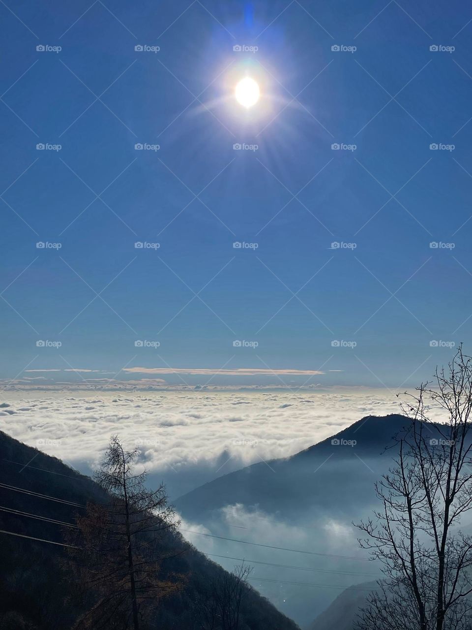 sun above the clouds, panorama from a mountain peak on a sunny day under a clear blue sky